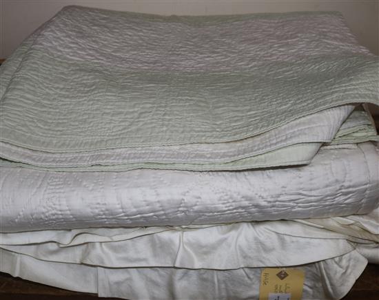 An off-white quilt with blue stitching, a reversible blue and cream quilt, a creamy oyster quilt and a mint green quilt (4)